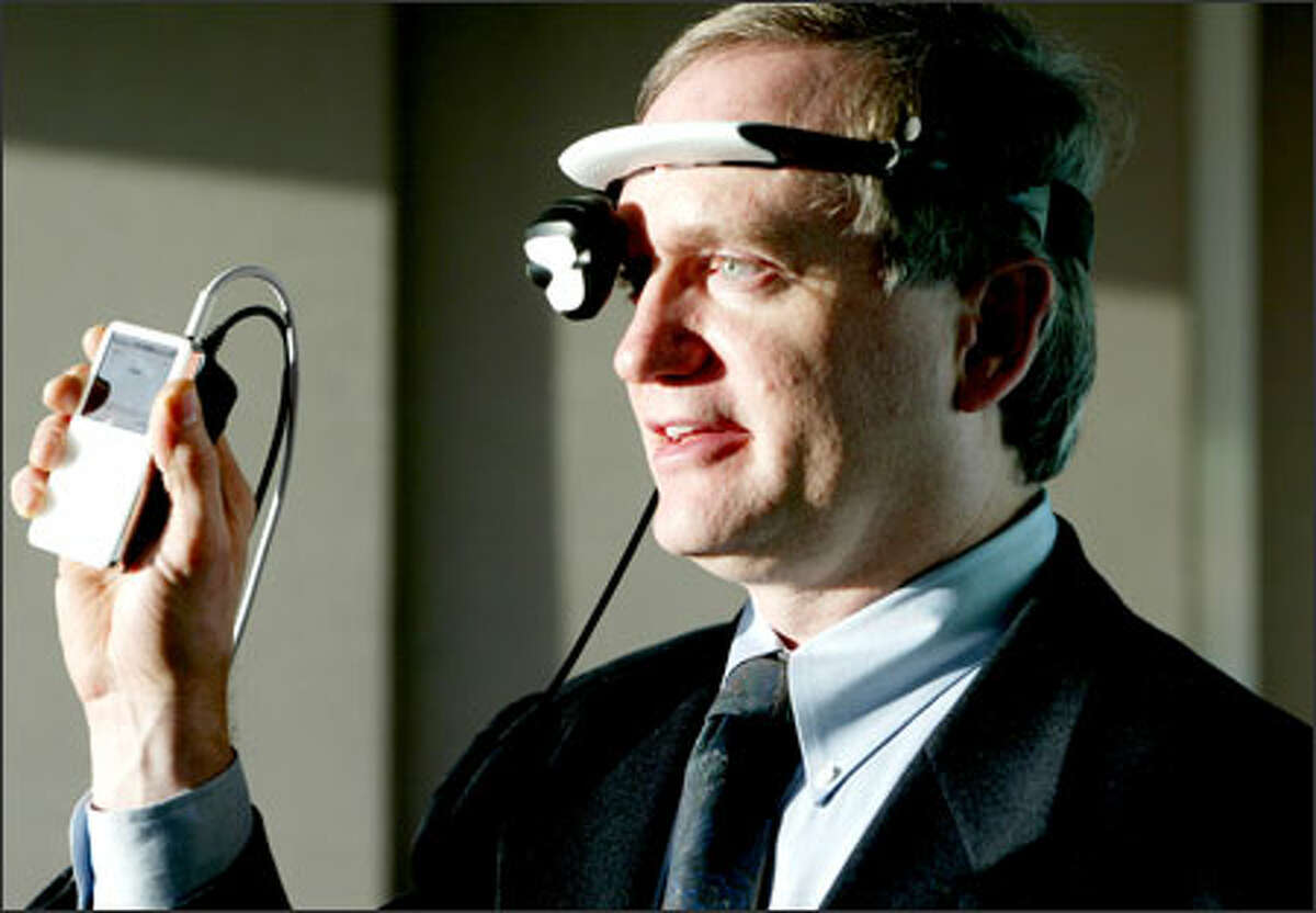 Gary Jones, president and CEO of eMagin Corp. of Bellevue, demonstrates his company's new wearable display for video iPods. Using the EyeBud headset is akin to watching a 105-inch display from 12 feet away. "Suddenly you've got this big-screen, movie-screen, home-theater experience wherever you are," he says.