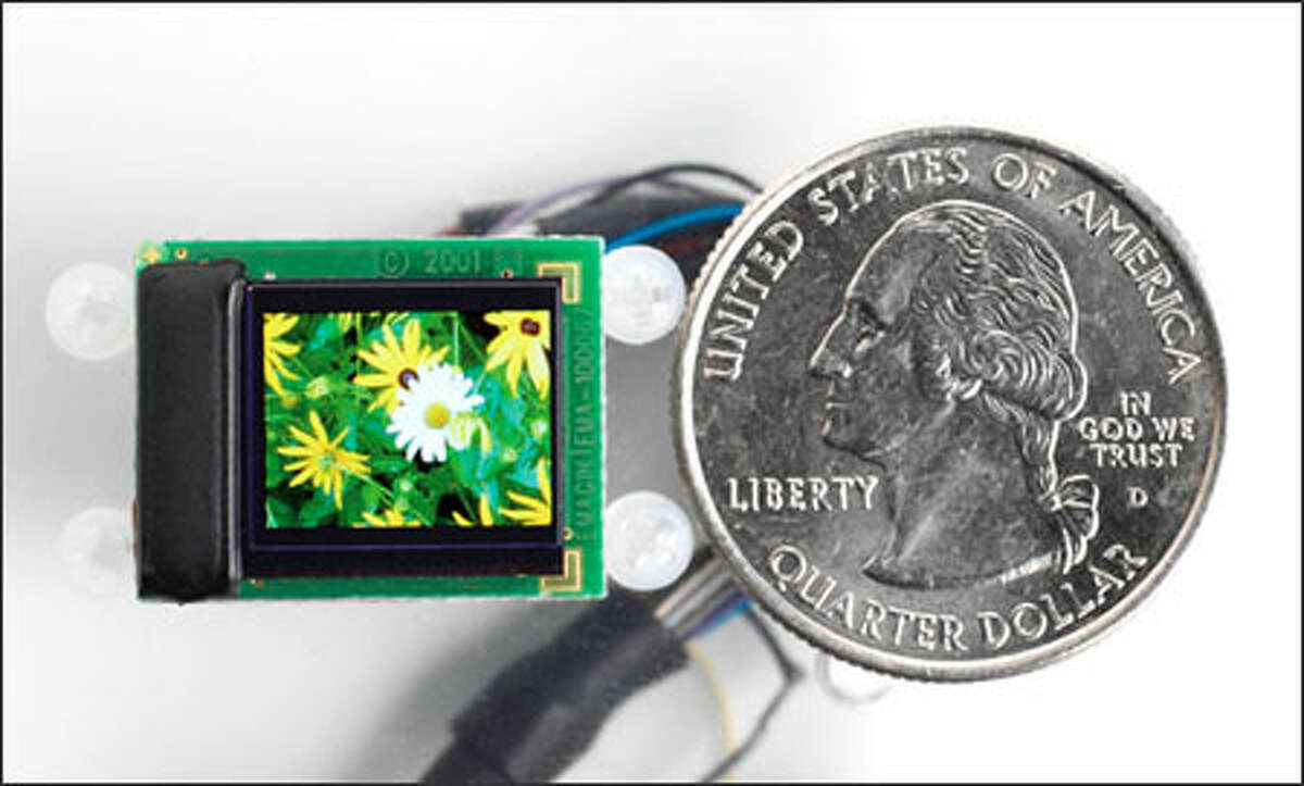A close-up of the display component of the new wearable display for video iPods by eMagin Corp., compared with the size of a quarter.