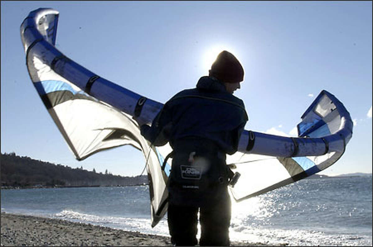 Terrance Towe carries his kite along the beach at Golden Gardens after a short kite boarding session on a windy Sunday. It was a frigid day: The temperature got up to just 27 at Sea-Tac Airport.