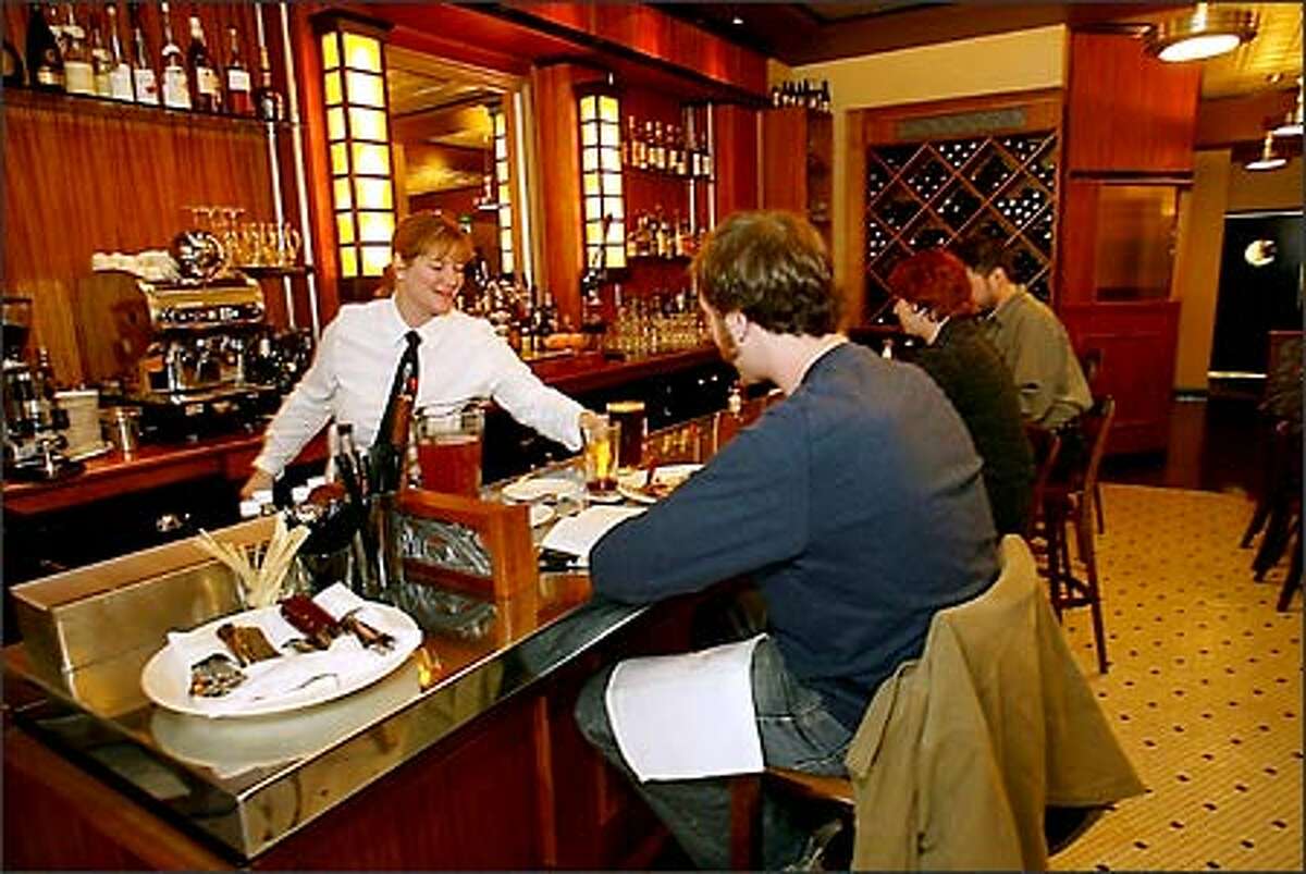 Gretchen Kenney, left, bar manager, serves a beer to Adam Levitt, center, at Bandol Restaurant while Monica Rasmussen and Alan Scott, far right, enjoy the moment.