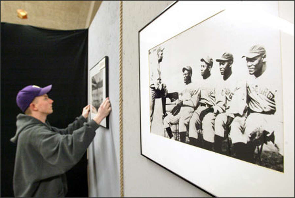 Paul Byrne, a 2002 graduate of Seattle's Chief Sealth High School, yesterday hangs a photo that is part of the Negro Leagues Baseball Museum's traveling exhibit. The Negro leagues were the only forum for black players until Jackie Robinson broke the color barrier in baseball in 1947.