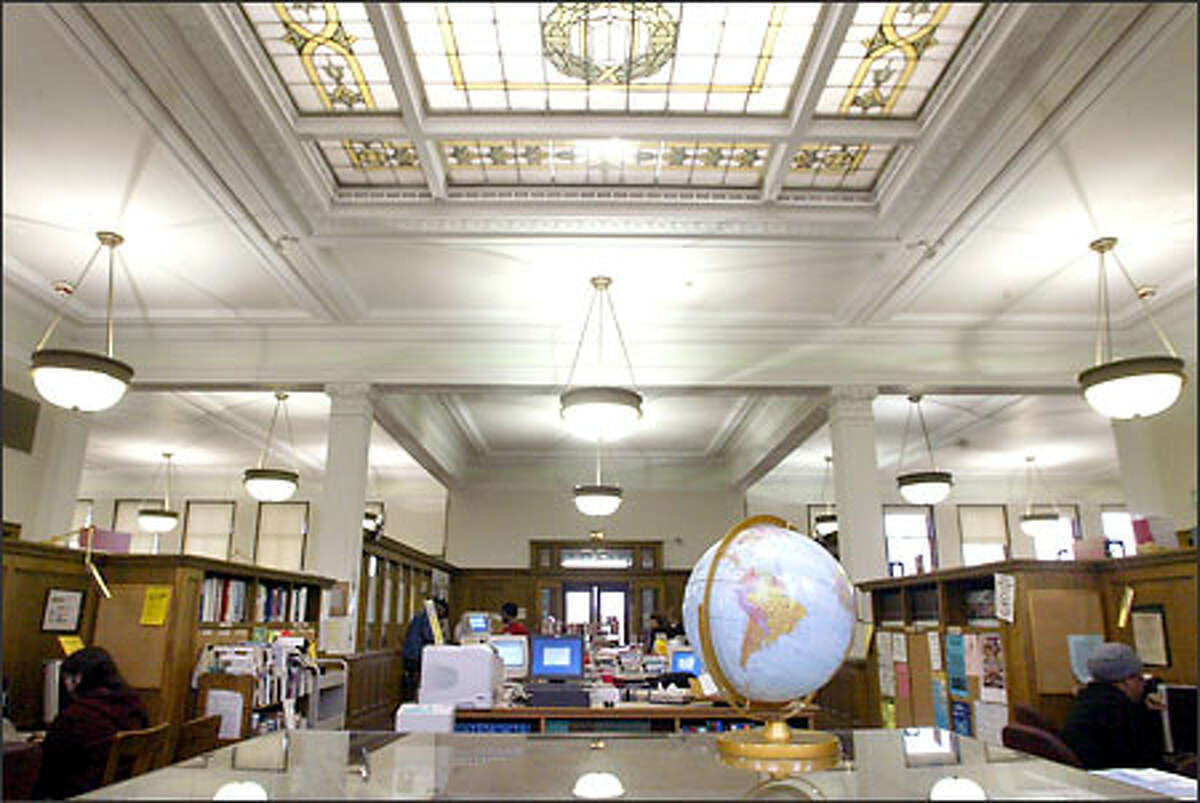 The interior of the Douglass-Truth Library in the Central Area looks spacious with its high ceilings and abundant lighting aided by the massive stained-glass skylight. Symmetrical reading rooms frame the east and west sides of the main entry. A third reading room on the north side is crammed with computers and book stacks.