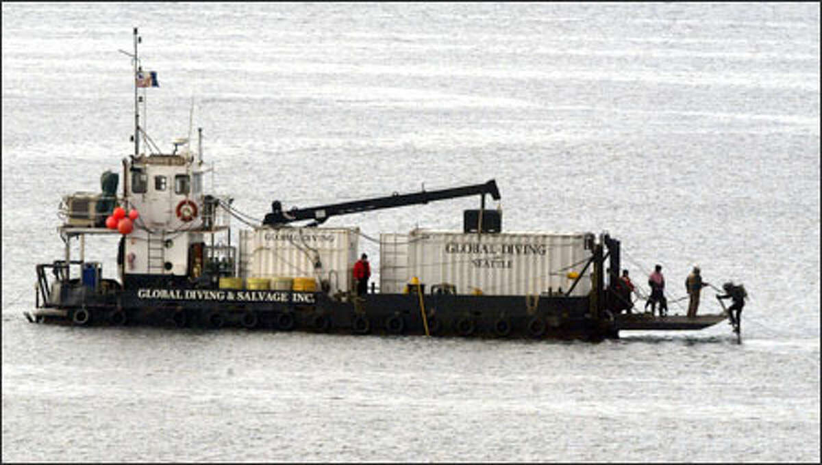 A diver returns from the waters of Elliott Bay to a support barge after inspecting the remains of two sunken decades-old barges just off Magnolia Bluff.