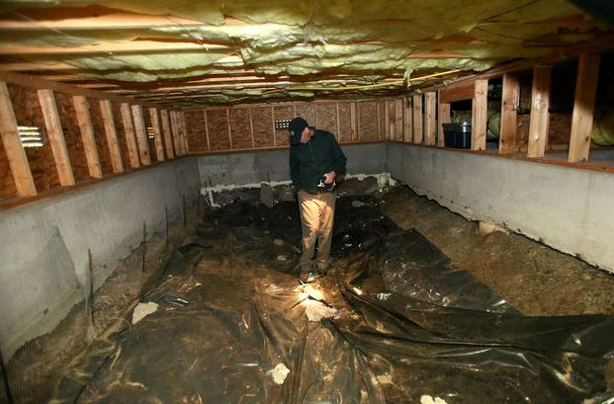 Alan Smith looks at the foundation in the crawl space of his Greenwood home.