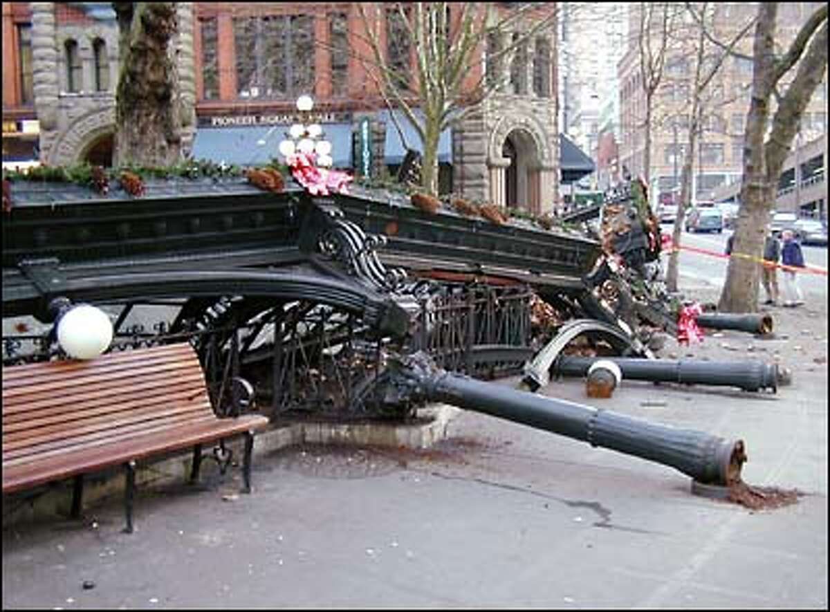 Still festooned with Christmas wreaths, the wreckage of Pioneer Square's historic pergola lies crumpled across the cobblestones.