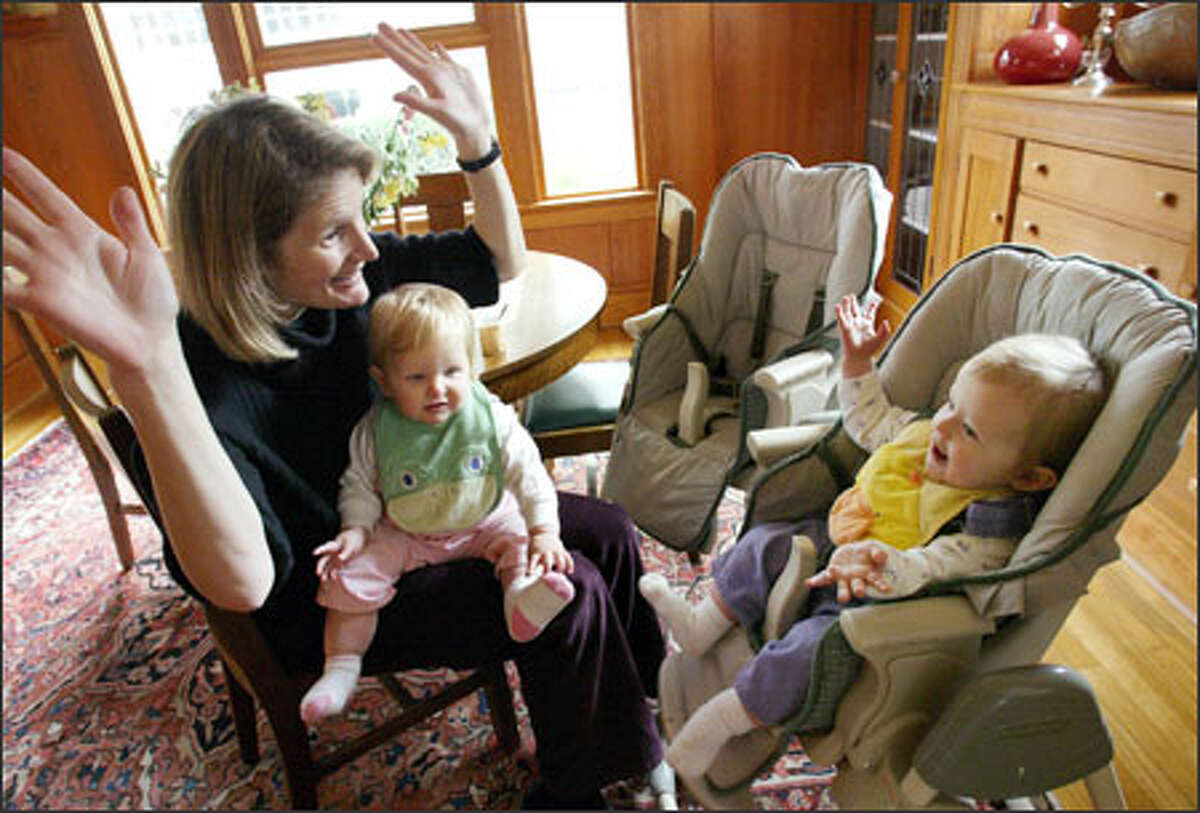 Jane Schmidt Campbell gets her daughter Esmé to sign "all done" while holding Esmé's twin, Madeleine, in their Mount Baker home on Tuesday. The girls are 11 months old.