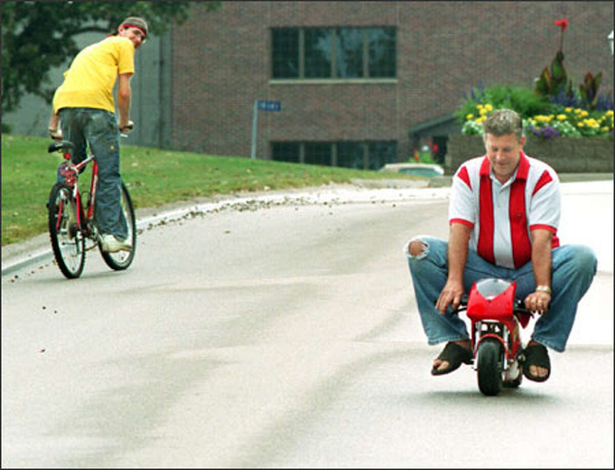 A bicyclist takes a second look at Tom Frick, riding a Blata minibike in Manchester, Iowa. The bike cost Frick $1,100, but some cost less than $200.