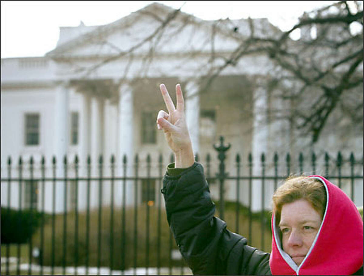 Anti-war protester Barbara McGovern, of Westfield, Mass., flashes a peace sign in front of the White House today. Thousands of people marched through the streets of Washington, D.C., this weekend to protest military action in Iraq.