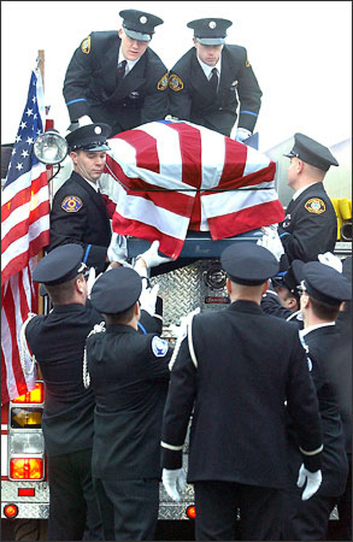The flag-drapped casket of Thad Dahl is lowered by his fellow Vashon Island firefighters as hundreds of friends and family turned out for Dahl's funeral mass held at St. Charles Church in Burlington, Wash.