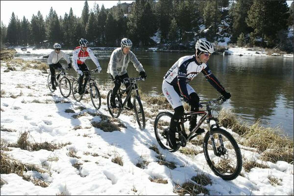 James Williams follows Ben Thompson past the Deschutes River on a ride through snow in Bend, Ore. The Winter Triathlon National Championship at Mount Bachelor is Feb. 9.