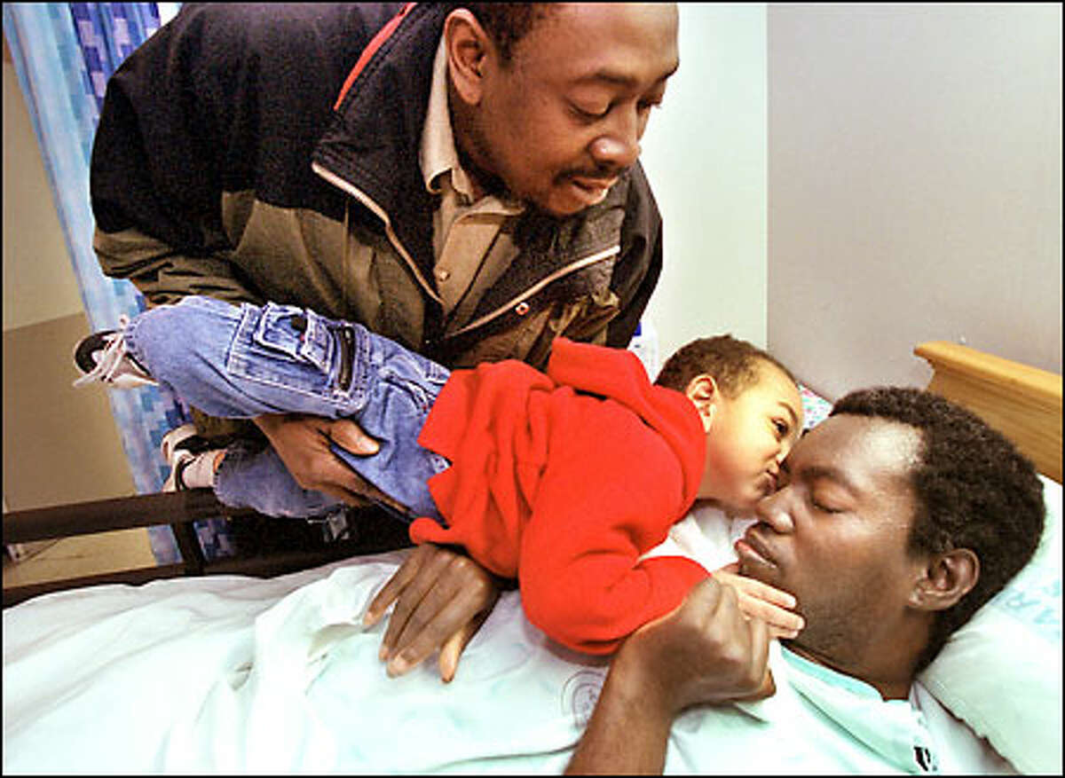 With his father Lee Watkins holding him, Isaiah Watkins, 2, kisses his uncle Freddie Watkins, a quadriplegic who was close to death when he was found neglected in his home.