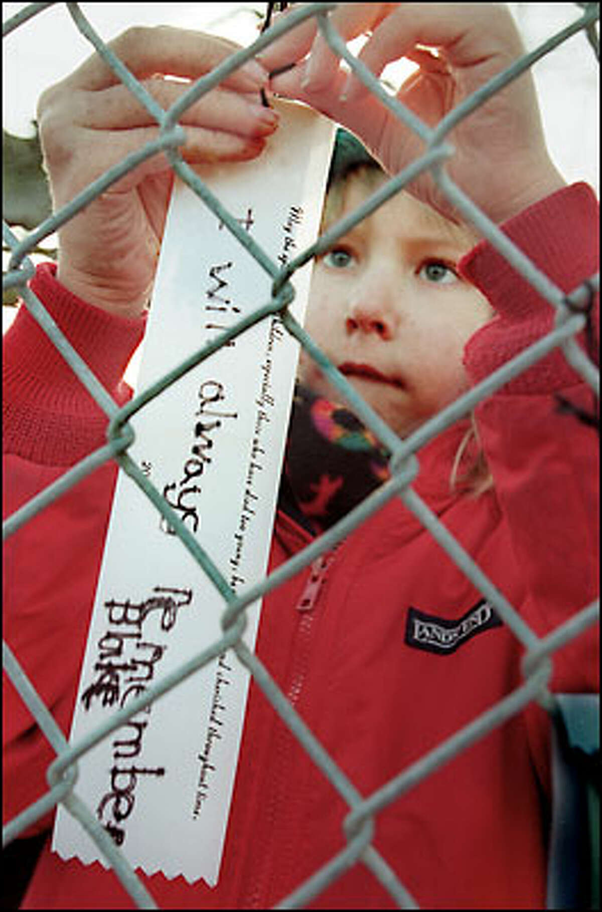 John Hay Elementary first-grader Corby Johnson ties a ribbon to a fence with a message to friend Blake Barnett-Clemetson, who died in the crash of Alaska Airlines Flight 261 in January 2000. The school broke ground on a memorial garden for crash victims yesterday.