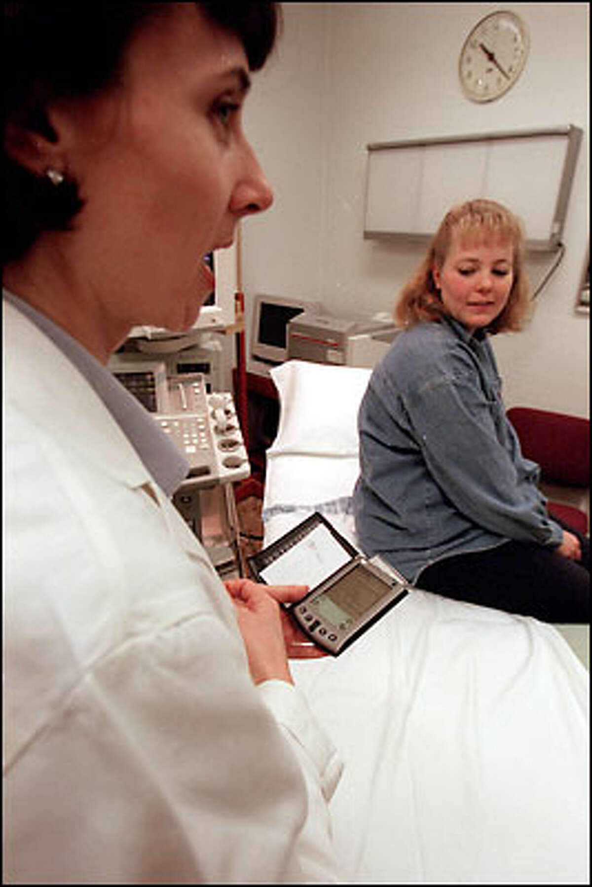 With her handheld Palm at the ready, Dr. Bettina Paek talks with patient Kelli Hall. The devices are so popular that the UW and Swedish Medical Center distribute them to all residents.