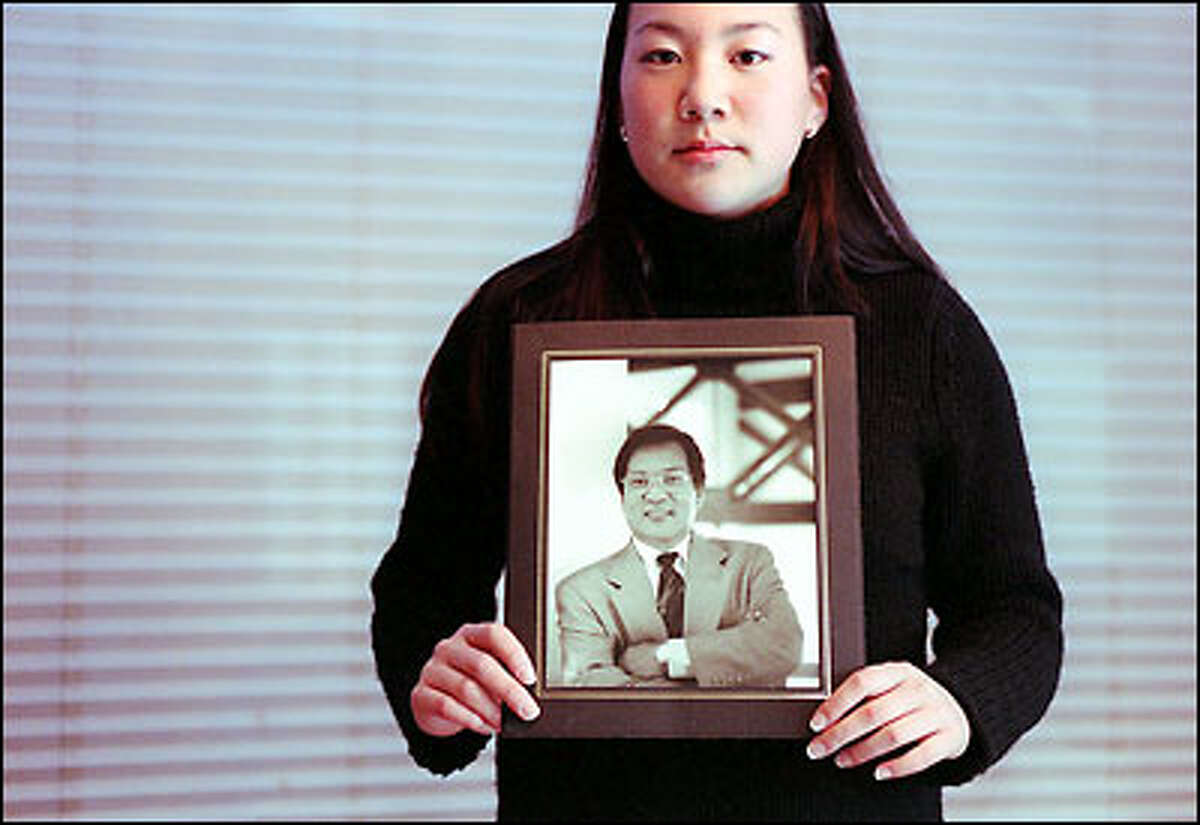 Sharon Kim holds a photograph of her father, Yongsu, who was slain three months ago outside his service station and convenience store. Sharon says she considered her father a best friend. "I just miss him so much. He was everything to me.&qu