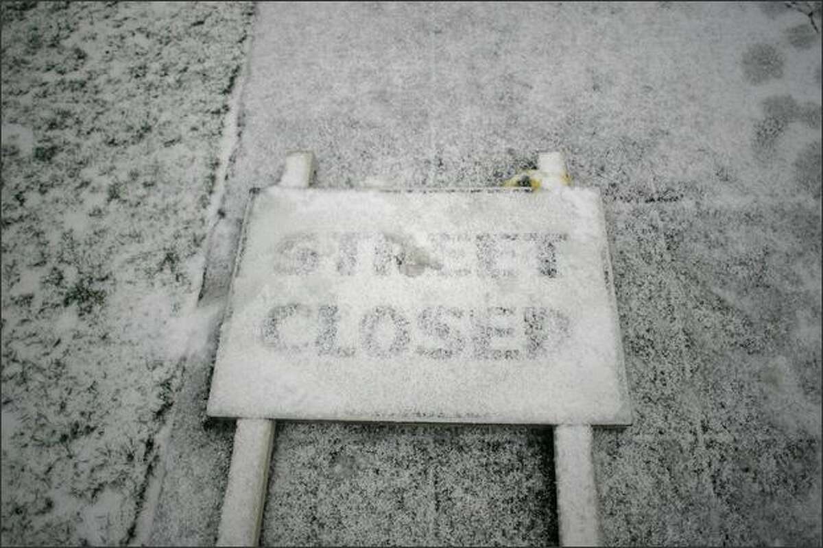Snow falls on a road sign in Queen Anne.