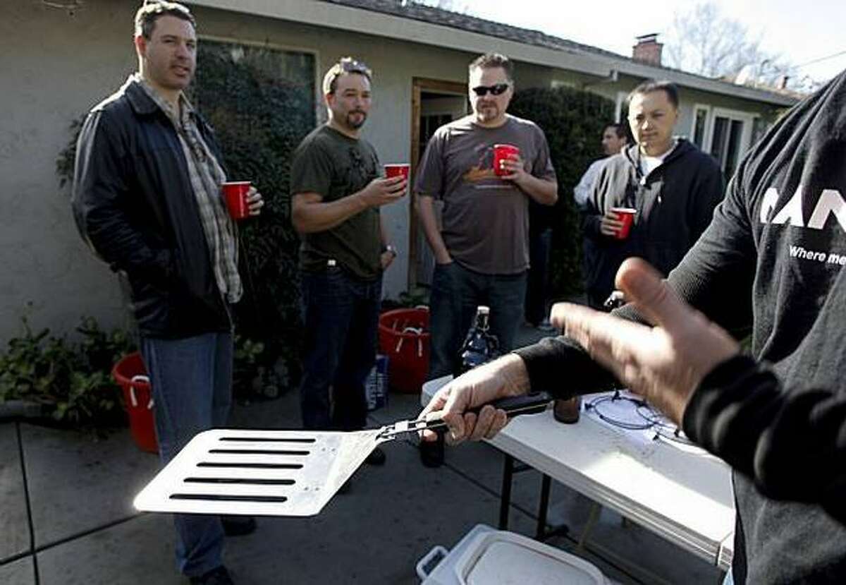 Man Cave salesman John Schaffran displays the $25, four-burger spatula that was one among many Man Cave barbecue products, which were available at this San Jose backyard sales party for men, a male version of the Tupperware party.