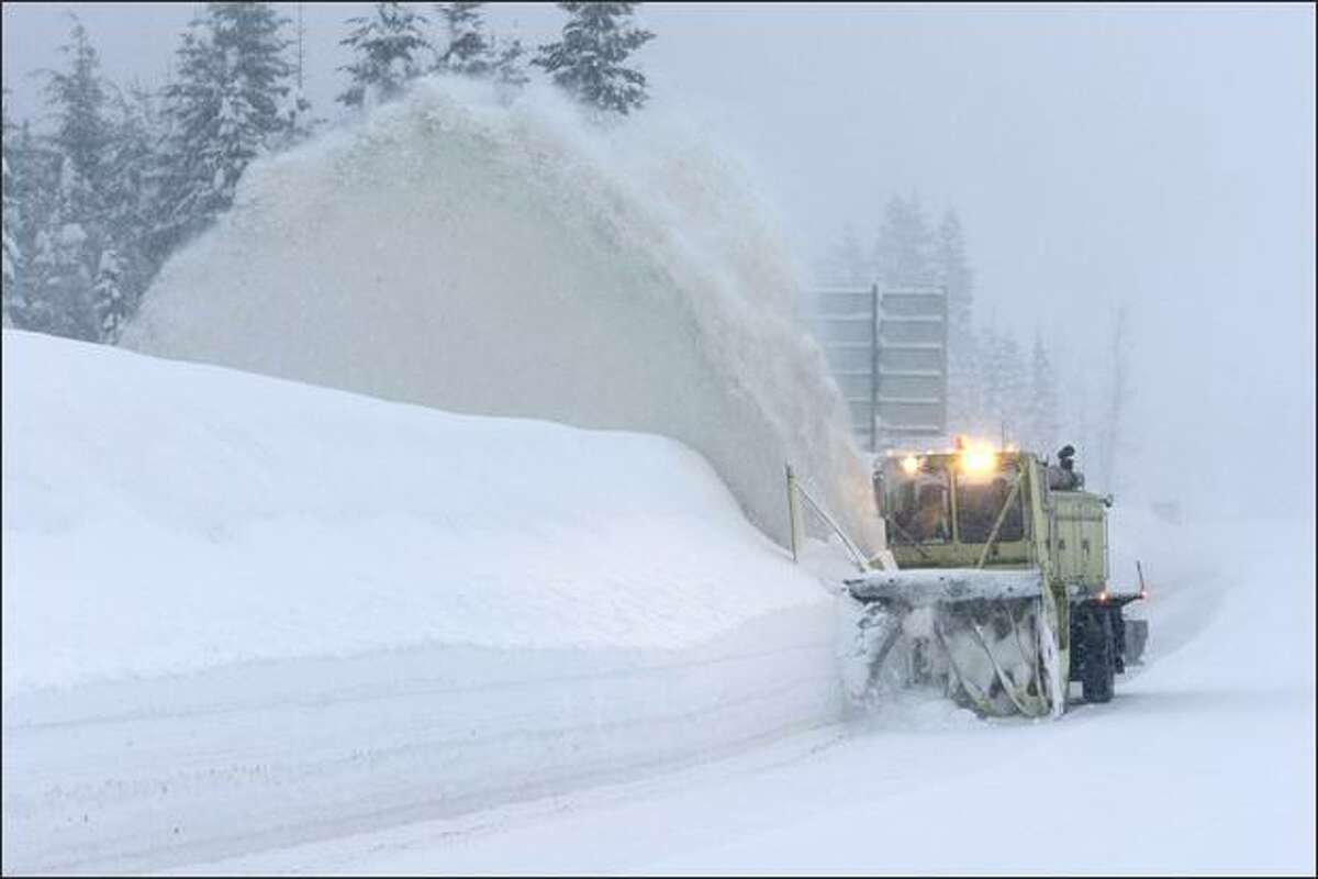A Washington State Dept. of Transportation snow blower clears the right shoulder of a closed portion of eastbound I-90 near the summit of Snoqualmie Pass Tuesday.