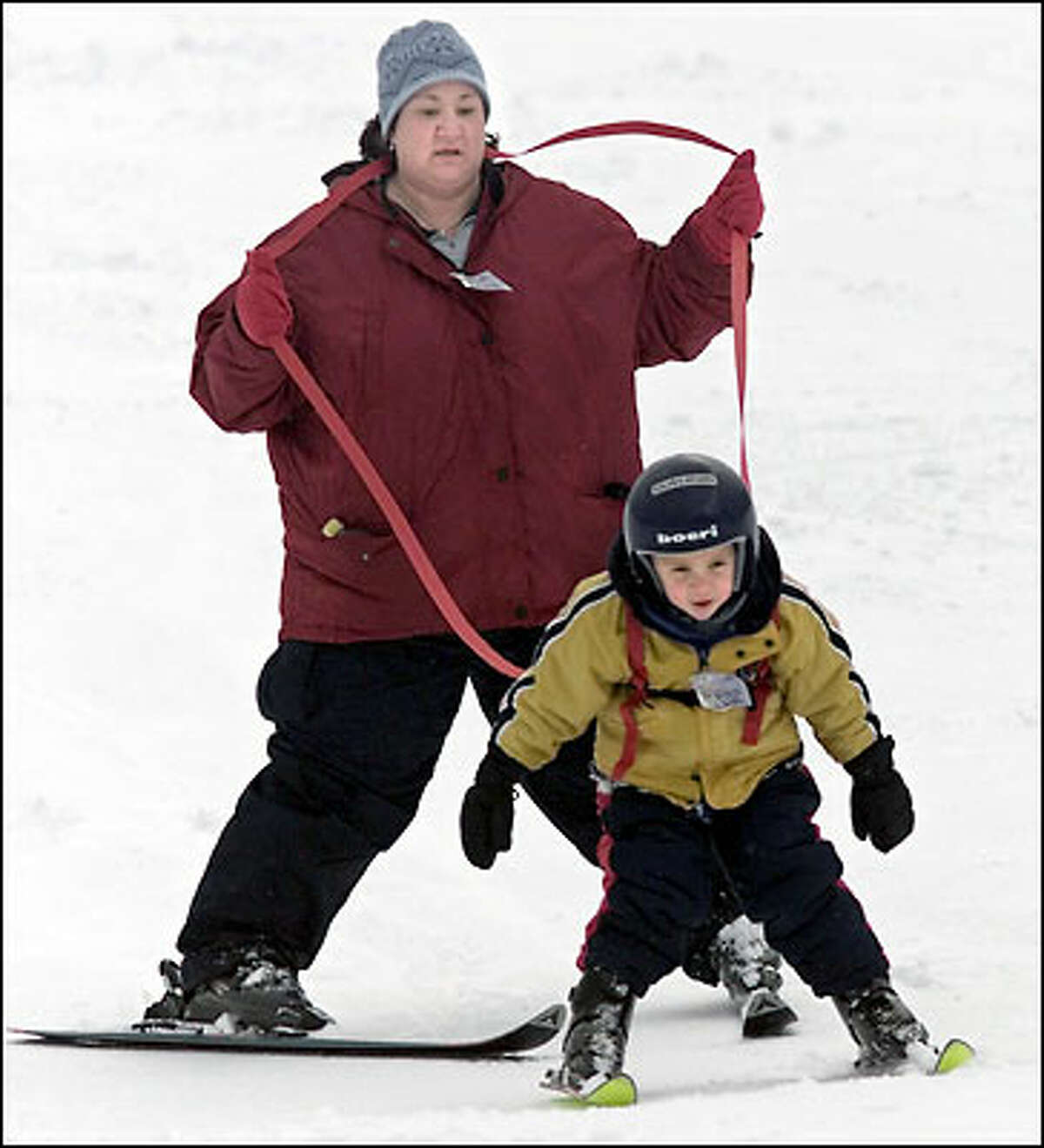 Tyler Thurman learns the ropes of skiing with his mother, Doreen. The 3-year-old would have preferred to snowboard yesterday at Snoqualmie Pass, but his mother advised skis first. Tyler's experience with ice hockey helped him look like a pro.
