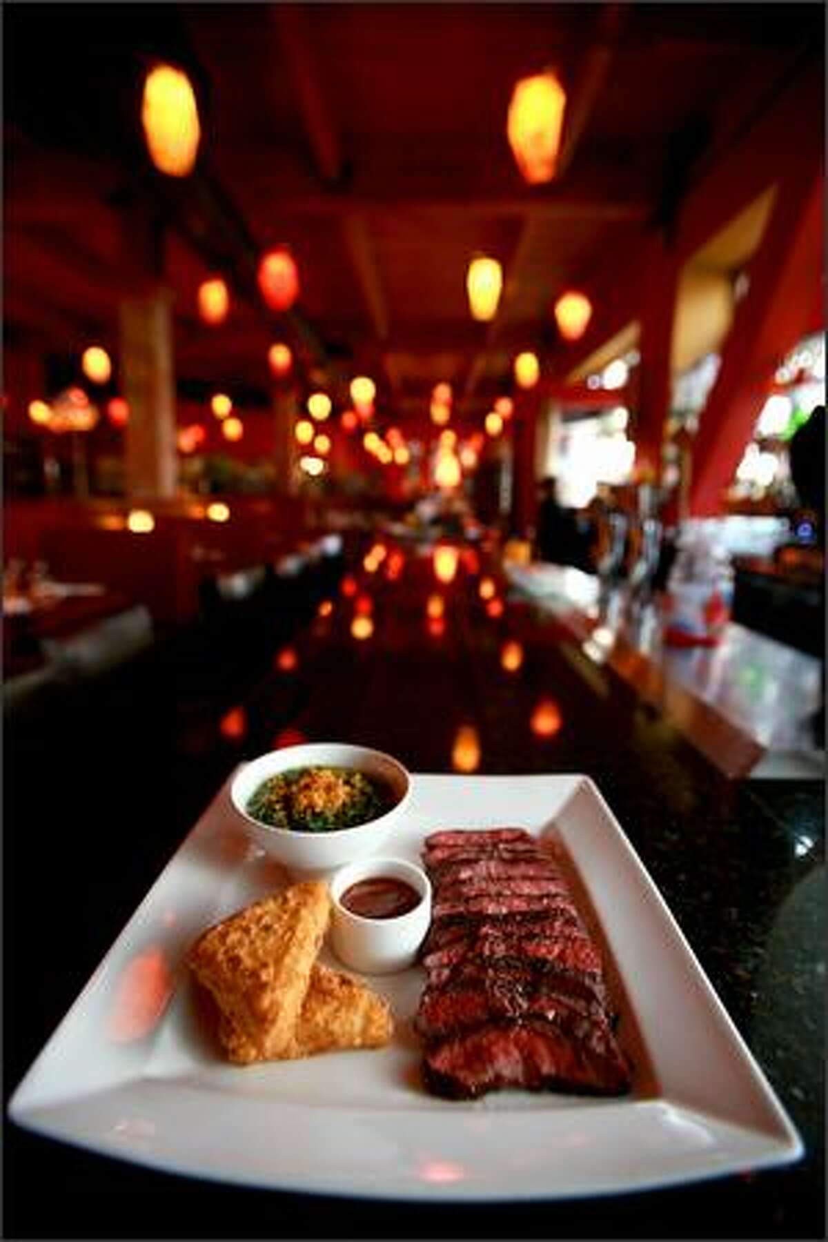 A tender flat-iron steak is served beside golden wedges of crispy grits and a small bowl of creamed spinach.
