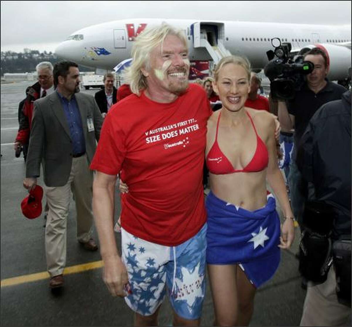 Sir Richard Branson, chairman of Virgin Group, walks with cabin crewmember Catherine Blackbee as they attend a delivery ceremony Friday for a Boeing Co. 777-300ER airplane in Seattle. The plane will serve the Los Angeles-to-Sydney route for Virgin's new V Australia airline.