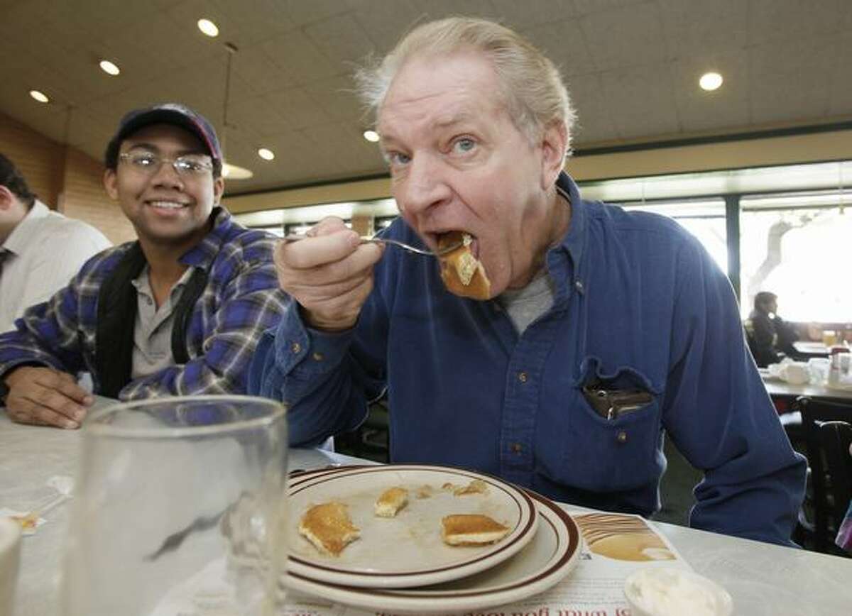Vince Briant, right, of Sun Lakes, Ariz., takes a bite out of his pancakes while Jon Steffen, of Mesa, Ariz., looks on as hundreds of patrons take advantage of the Denny's free Grand Slam breakfast national giveaway at a local Denny's restaurant in Tempe, Ariz., on Tuesday. (AP Photo/Ross D. Franklin)