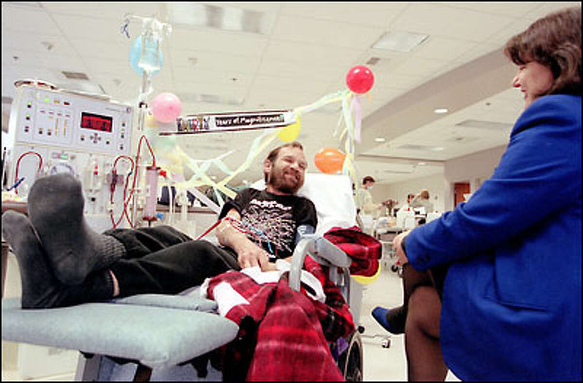 Mike Matson receives kidney dialysis at Olympic View Dialysis Center and a visit from his sister, Laura Matson, to make the five-hour ordeal go easier. He has lived with dialysis for 30 years, as the celebratory balloons and ribbons attest.