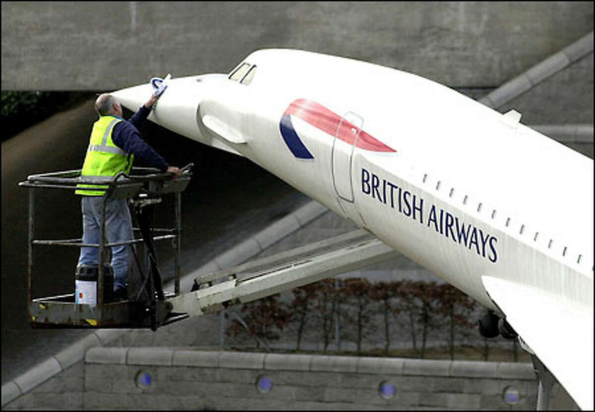 A British Airways worker cleans a model of the Concorde at the main entrance to London’s Heathrow Airport yesterday. After years of pinning its fortunes to the deep pockets of business-class travelers, British Airways announced a strategic flip-flop, saying it would seek to compete with Europe’s booming, low-cost airlines by offering cheaper travel over the Internet to passengers in coach. The airline also said it would cut 5,800 more jobs.