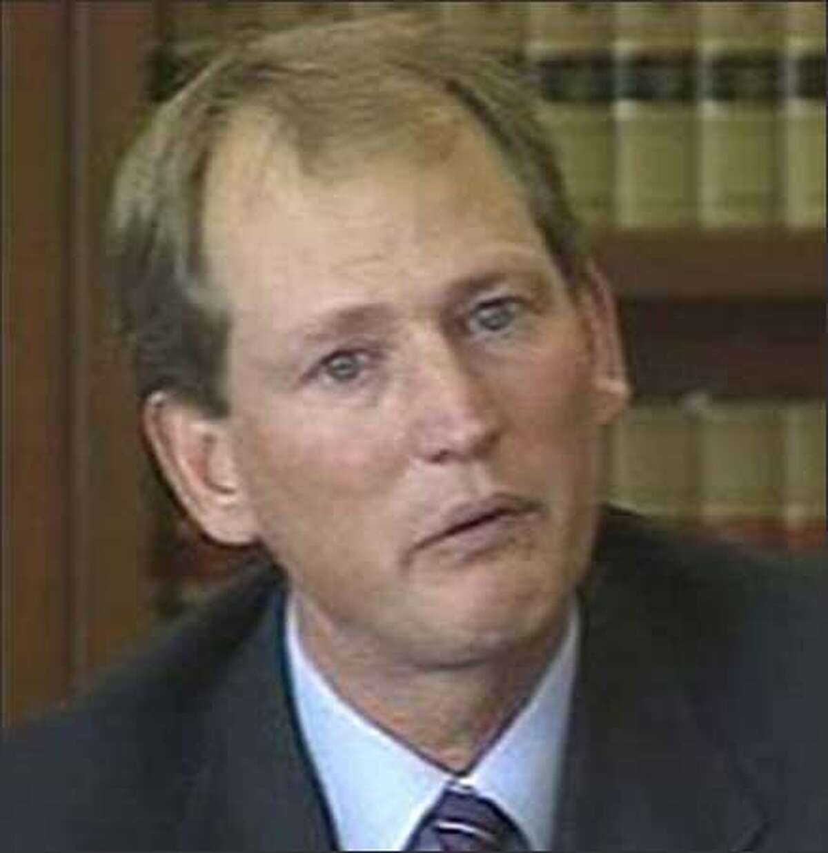Former UW Coach Rick Neuheisel cries on the witness stand; photo taken from video.
