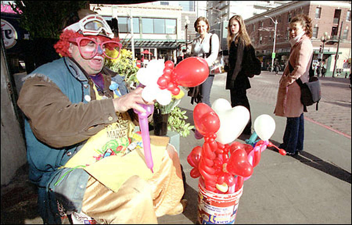Balloon artist Ferrel Thomas, aka “Thomas the Twister," whips up another of his creations as Erin Nacey, left, Heather Whitehurst and Michelle Flickinger watch during a sunny-day visit to the Pike Place Market yesterday. Rain is scheduled to arrive today. Thomas doesn’t charge for his balloon art but he does accept donations.
