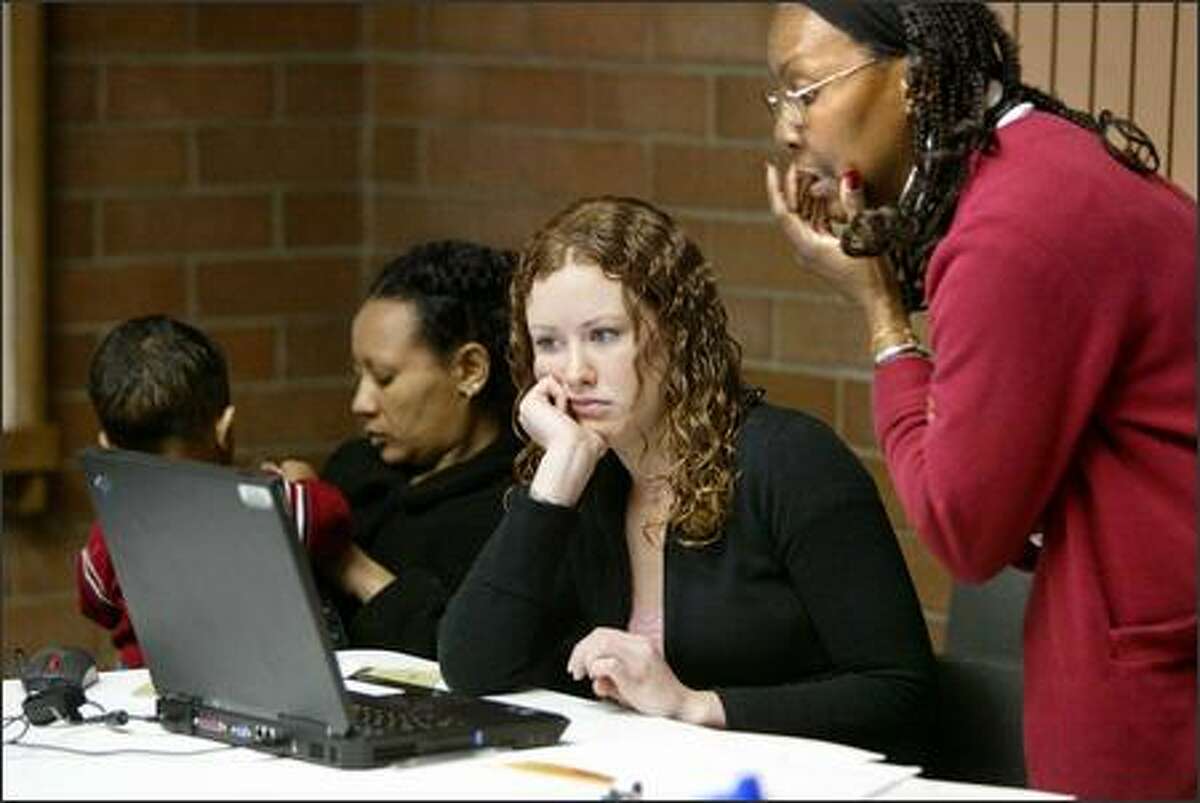 Tamera Kelly, center, and Andrea Shirley, right, work on preparing taxes for a woman at the library.