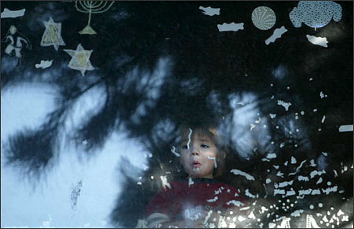 Under the Star of David, a child peers out a second floor window of their home at 1408 NE 65th St. as the FBI's Joint Terrorism Task Force conducts a raid. Agents arrested a neo-nazi tennant who lived in the apartment below from which a small arsonal of weapons was recovered on Tuesday.