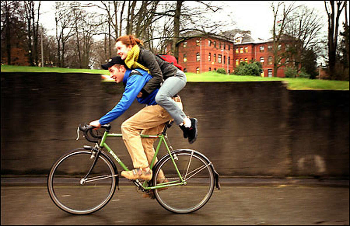 Adrian Hegywary, 18, carries some extra baggage – his friend Neysa Bell – up a hill on 15th Avenue Northeast near the University of Washington campus. Bell, 18, piggybacked home because it was quicker than walking and lessened the amount of time she had to be in the rain. Today’s forecast calls for more lingering showers with a high of 51 degrees.