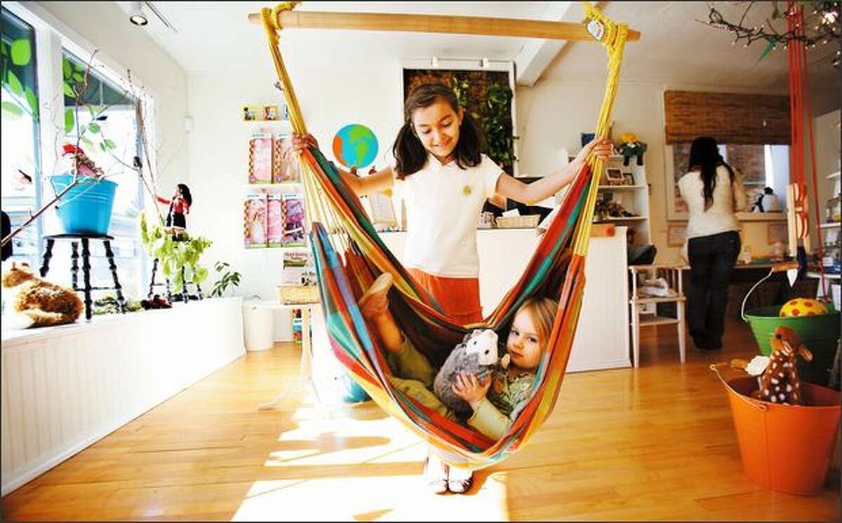 Isabella Faget, 3, tries out the hammock at Planet Happy Kids in Ravenna on Friday with the help of Hannah Kohrmann, 10. The showroom for the larger online company sells fair-trade, organic, socially responsible, natural and green products for children.
