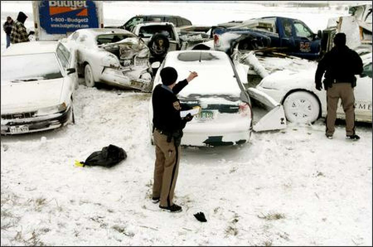 Aaron Limburg, of the Colorado State Patrol, takes notes at the scene where more than two dozen cars collided in whiteout conditions on Interstate 70 early Saturday in Aurora, Colo. Blowing snow reduced visibility to almost nothing when the accident happened. No major injuries have been reported in the pileup.