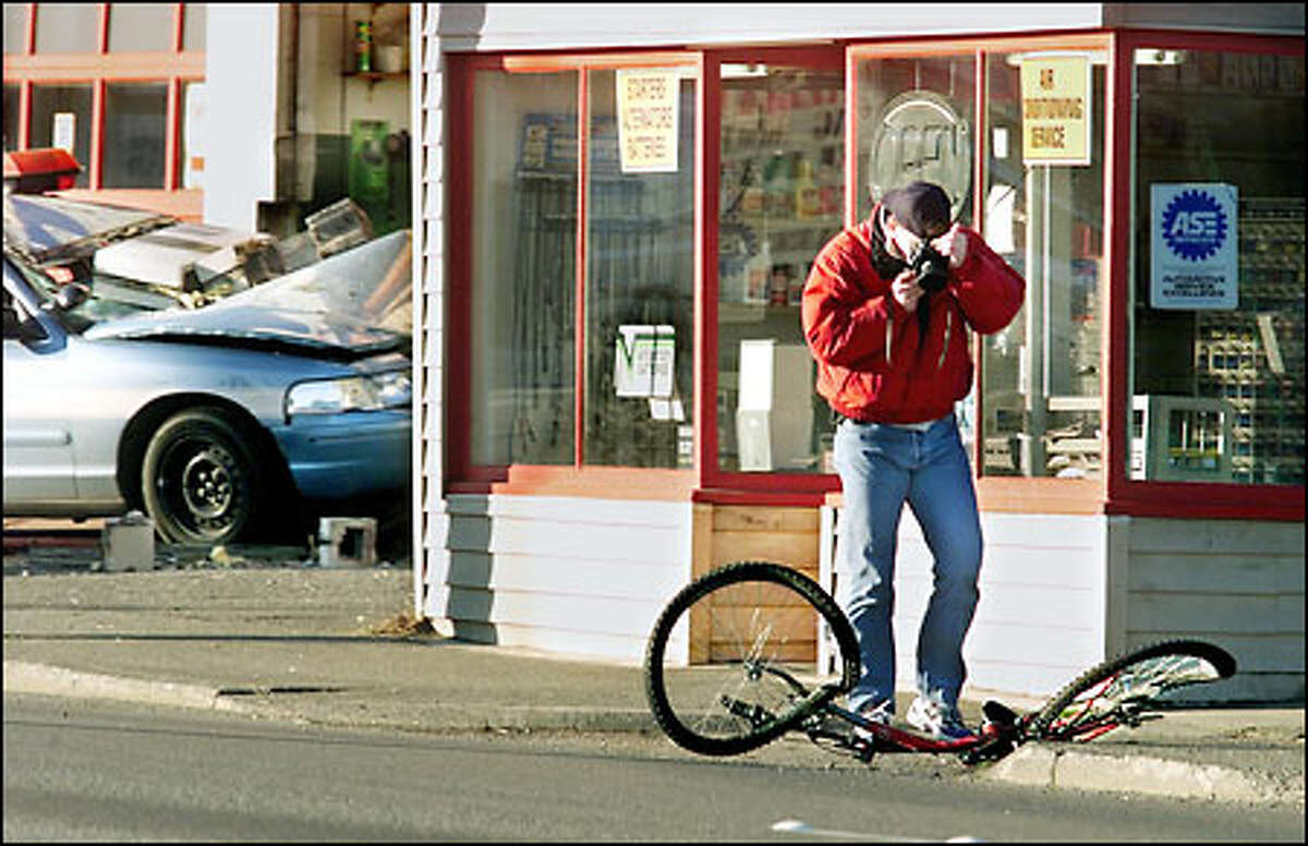 Seattle Police Detective Randy Huserik photographs the bicycle of a man who was fatally injured in a crash with a police cruiser, shown in the background, early yesterday.