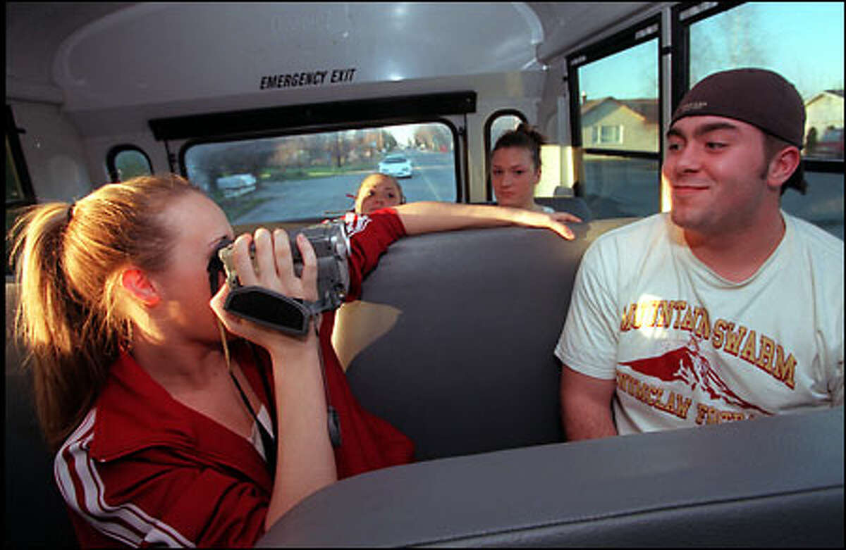Brittney Osborn videotapes Jacob Wasson on the bus to the Tacoma Dome, where the Enumclaw boys' and girls' basketball teams will play in the WIAA 4A Basketball Championships.