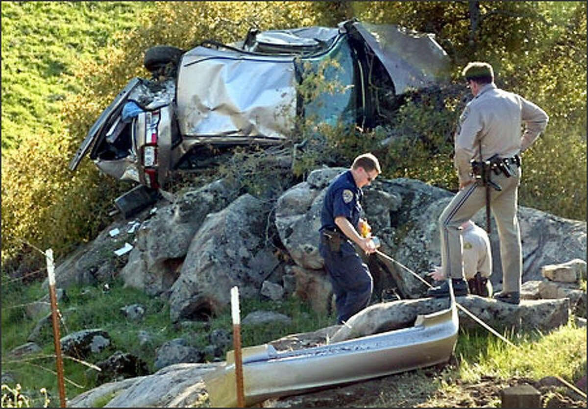 California Highway Patrol officer Ron Krider, left, stretches out a tape as he measures the distance from the roadside to the final resting place of a car along Highway 41, Thursday, March 6, 2003, near Coarsegold, Calif. The woman driver ordered her three children to unbuckle their seatbelts and then steered her car off a 40-foot cliff, killing herself and seriously injuring the youngsters, police said Friday. The other officers are unidentified.