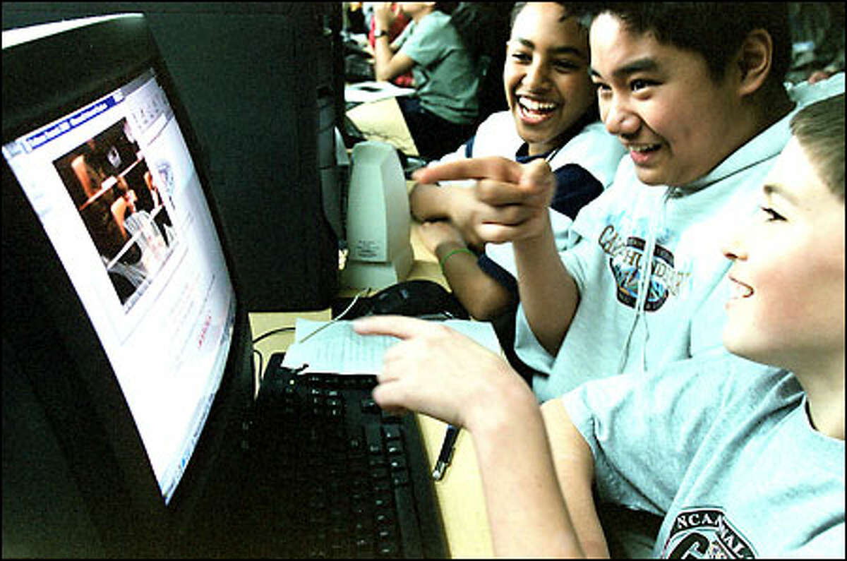 McClure Middle School sixth-graders Colin Dunphy, foreground; Tim Ramos, center; and Haben Sebhatu get a kick out of seeing one of their classmates on an online videoconference hookup from an international salmon summit.