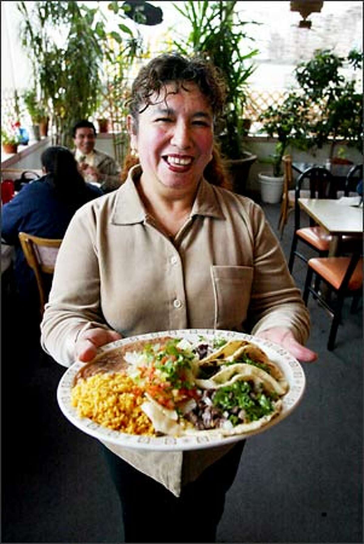 Elvira Lohman, owner of Coliman Restaurant & Taqueria in Georgetown, shows off one of her signature dishes, a steaming plateful of Tacos de Carne Asada.