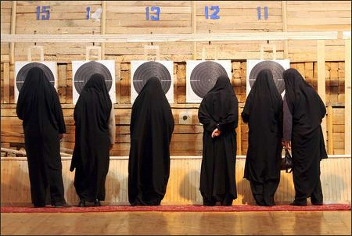 Wearing chadors, Iranian female paramilitary volunteers, Basiji, check the targets after shooting in a competition in Tehran. (AP Photo/Vahid Salemi)