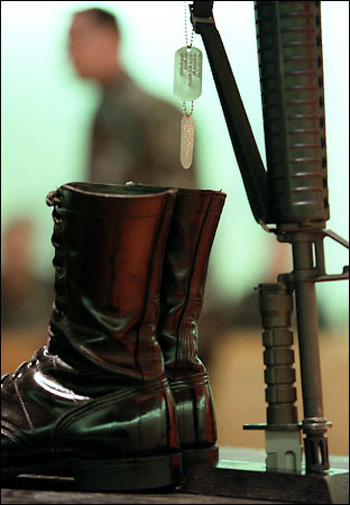 Inside the Soldiers' Chapel at Fort Lewis, the symbolic boots, dog tags and inverted rifle with helmet form the centerpiece at a memorial yesterday for 29-year-old Army Spc. specialist Jason Wildfong, who was one of six military observers, including five Americans, killed by friendly fire during a training accident in Kuwait on Monday.
