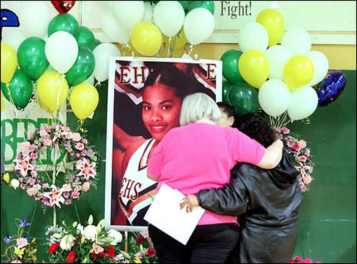 Evergreen High School cheerleading coach Terry Dixon, left, hugs Josie Grace Peterson's mother, Mary Marrero, in front of a photo of Peterson.