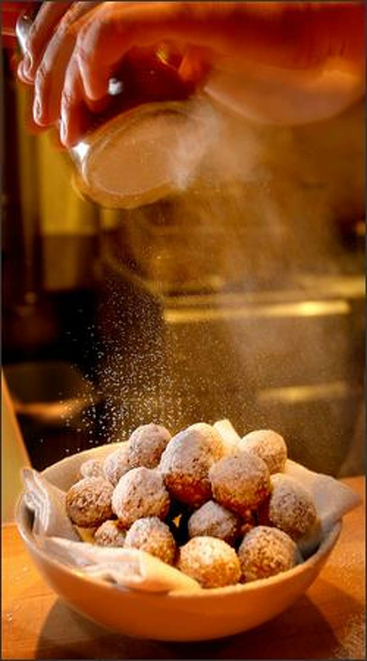 Powdered sugar is sprinkled on an order of zeppole, a generous mound of lemony doughnut holes.