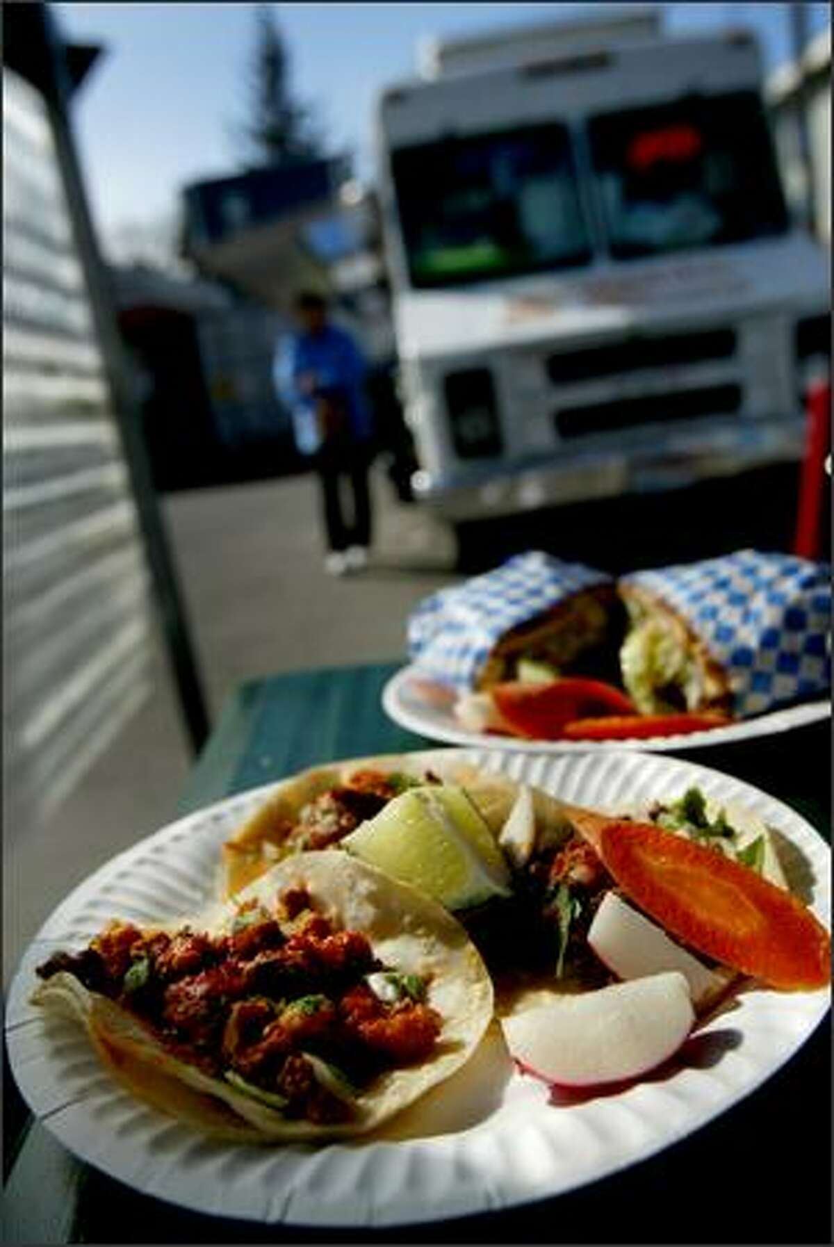 Birria (spicy Mexican meat stew) and tripe tacos, in the foreground, and a chicken torta plate from the Taqueria El Rincon taco truck in South Park.