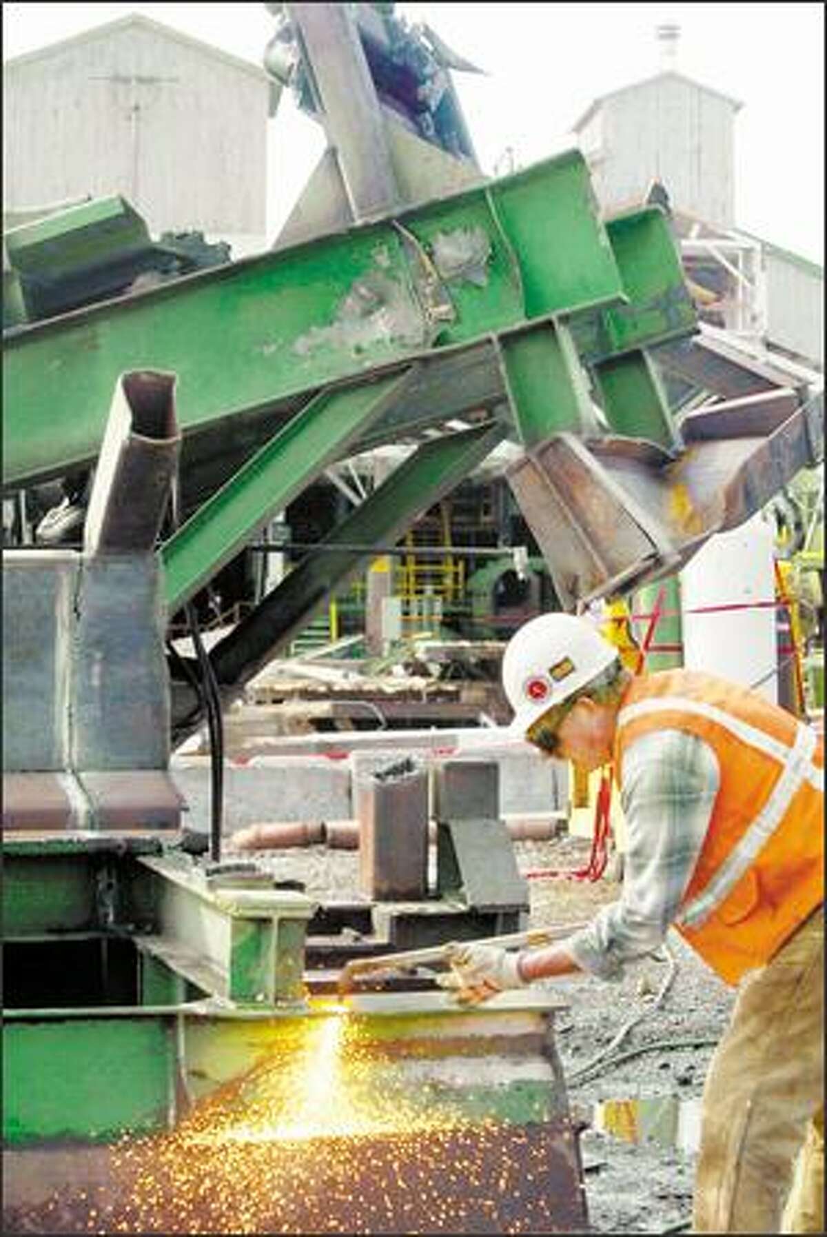 John Schneider with Staton Cos., a demolition firm, cuts up a large steel beam that was removed from the closed Weyerhaeuser mill near Enumclaw. Steel, wood and even concrete will be salvaged and reused.
