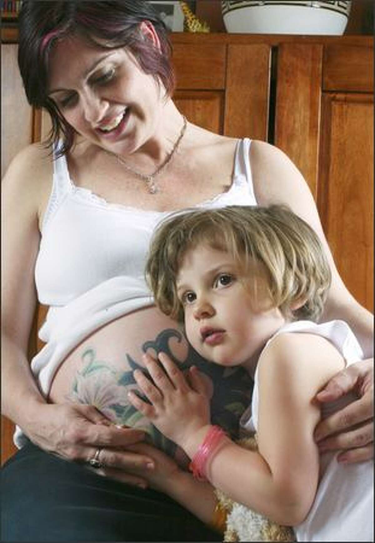 Sadie Botuchis, 3, listens for signs of life on mom Kristin Botuchis' tattooed belly in their Seattle home. Becoming a mom was a transition for Botuchis, who used to go out every weekend to clubs all around town.