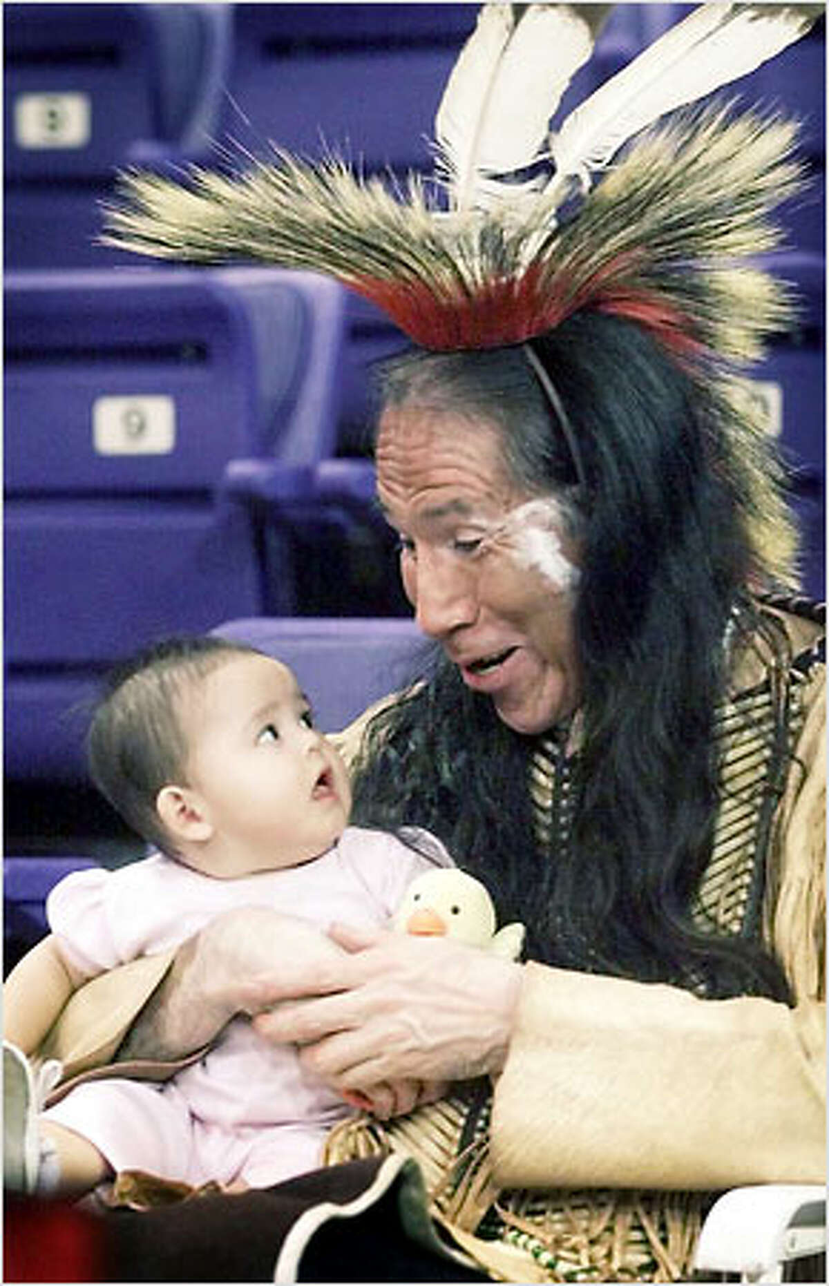 Bob Red Elk, of Beacon Hill, bounces his granddaughter Shana George, 6 months old, on his knee to the beat of dancing drums during the "Pow Wow at the UW" held yesterday at the Bank of America Arena on the UW campus. Red Elk, a Lakota Dakota, was among more than 200 dancers from across the nation competing in the gathering.