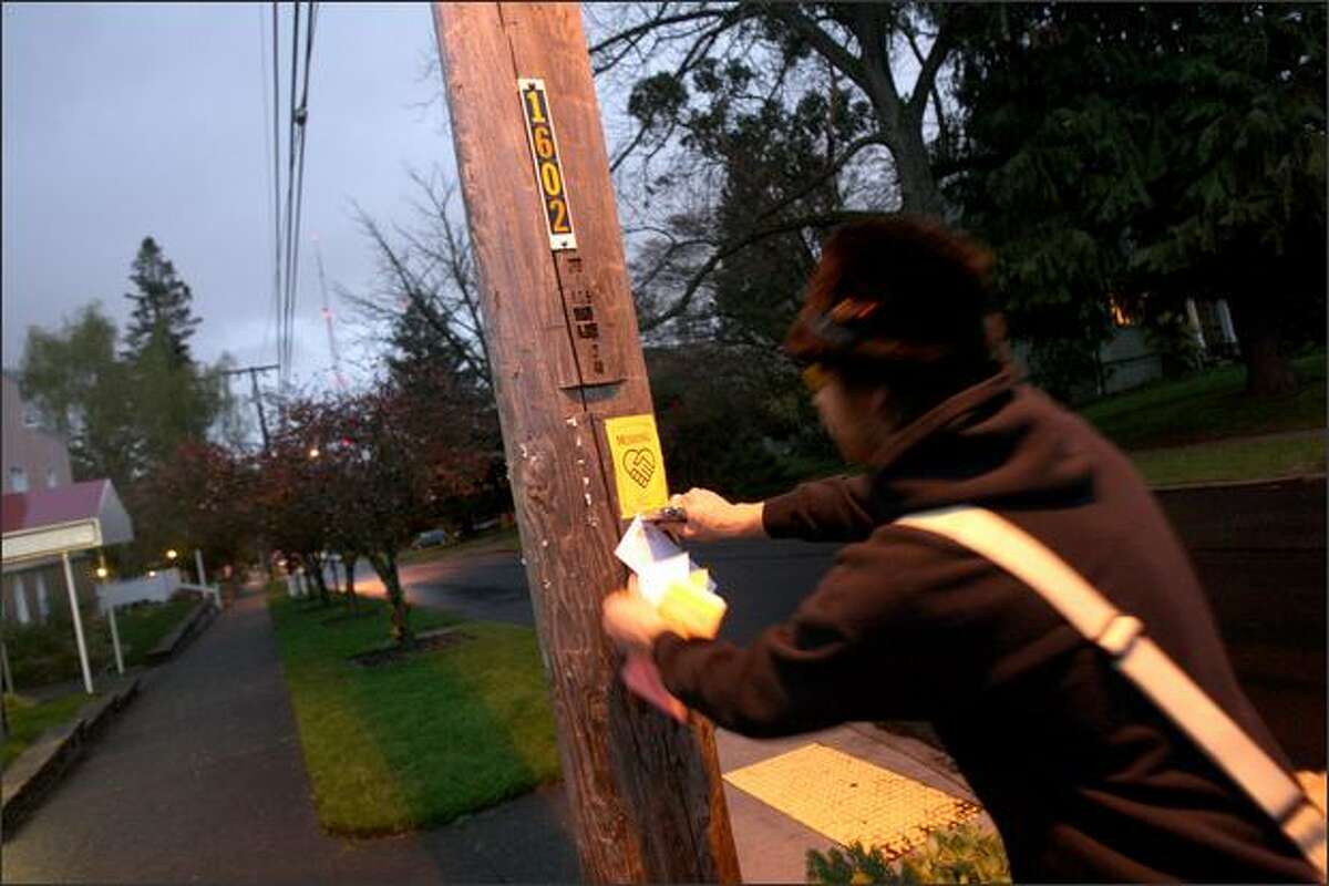 Queen Anne resident Gabe Johnson staples fliers and copies of an essay by Hunter S. Thompson to telephone poles Tuesday. He's a member of a group called the Comstock Commission, which is trying to promote creative interaction among a Queen Anne set it sees as a bit stuffy.