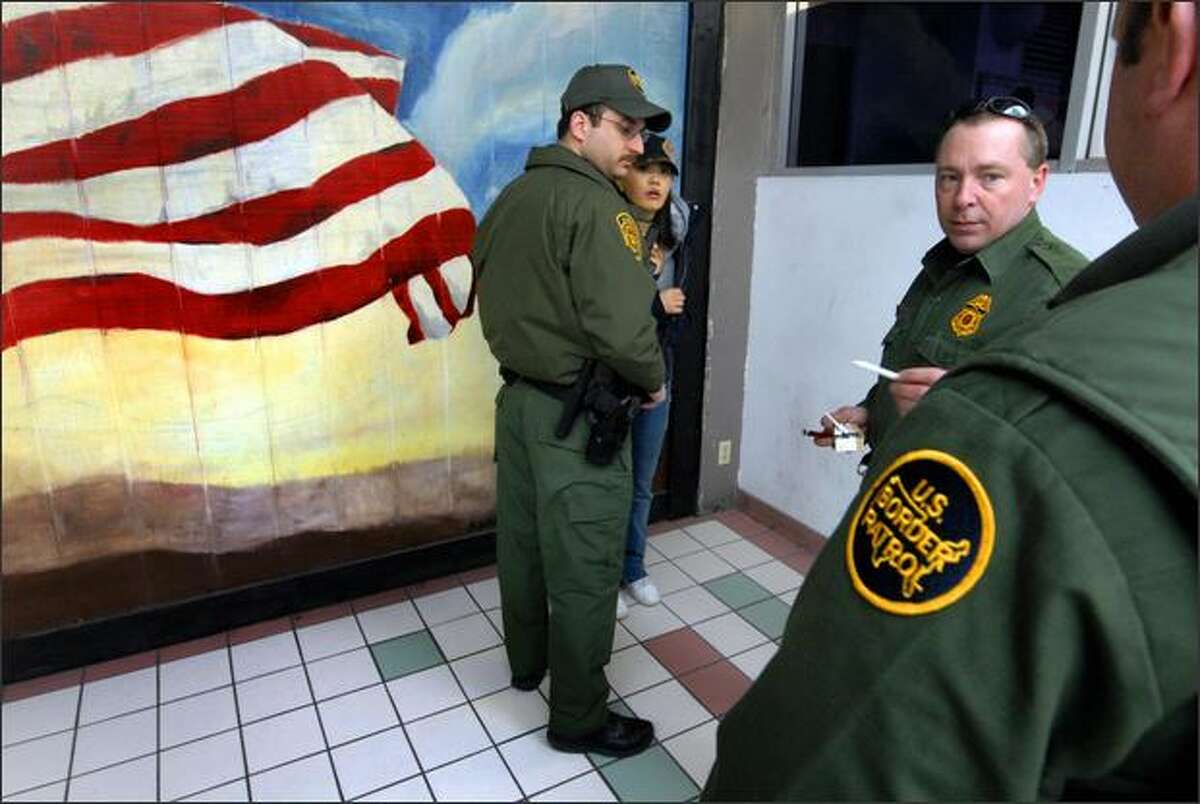 U.S. Border Patrol agents, left to right, Eric Klien, Clay Linn and Chad Cadwallader question a tourist from China after marijuana was found in her luggage at the Rochester, N.Y., bus station.