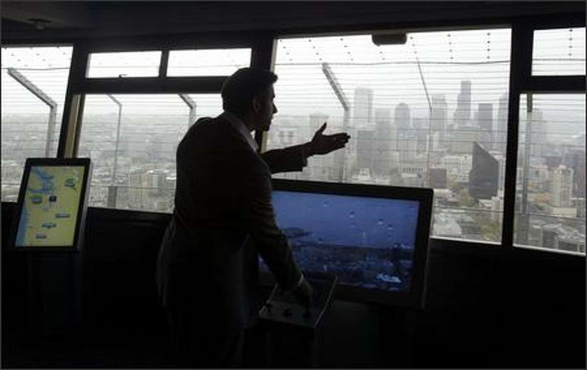 Eric Perret, SkyQ project manager, demonstrates some of the new technology geared toward tourists visiting the Space Needle at a prelaunch briefing Tuesday. SkyQ, a $2 million project that includes five interactive kiosks giving visitors atop the Space Needle the opportunity to view Seattle in unique ways, will open to the public today.